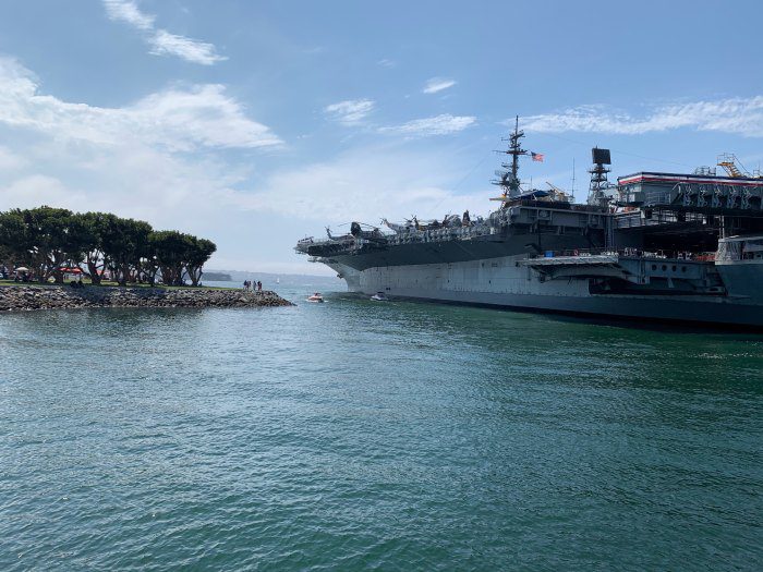 A large ship in the water near some rocks.