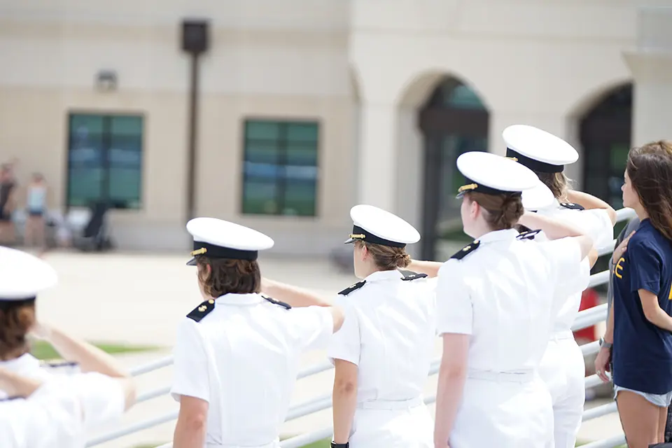 A group of people in white uniforms saluting.