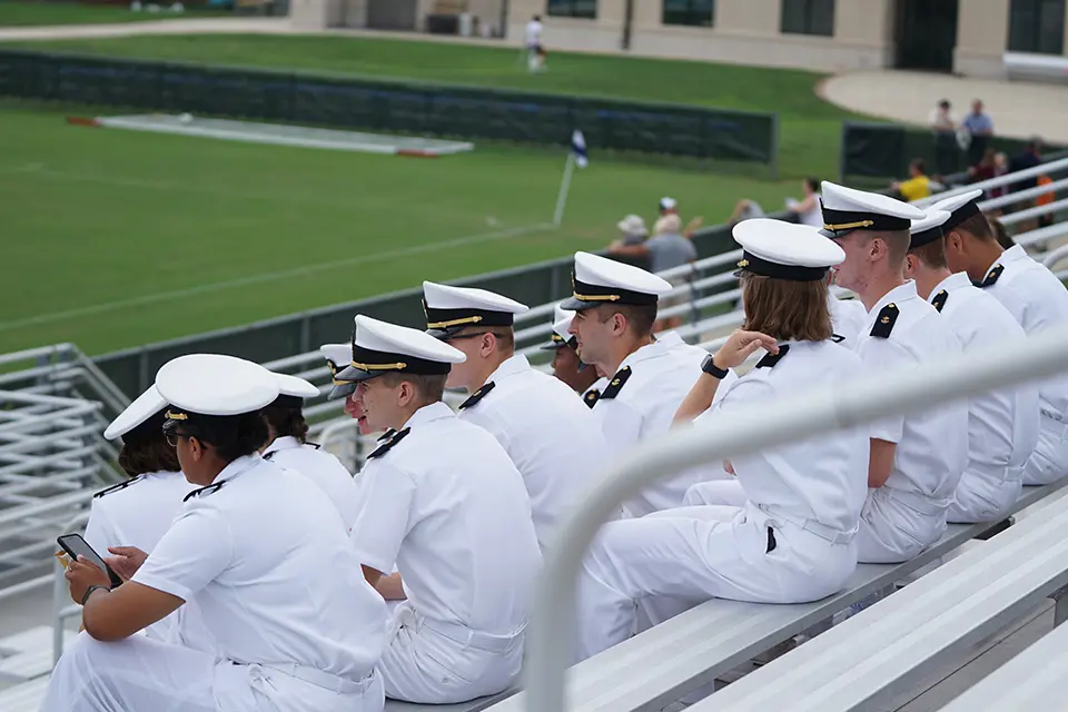 A group of sailors sitting in the bleachers.